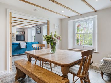 A dining room with a table and flowers at Treovis Cottage in Callington