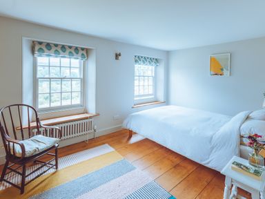 A bedroom with a bed and chair at Treovis Cottage in Callington