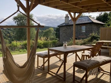 An outdoor seating area with a hammock and table at Treovis Cottage in Callington