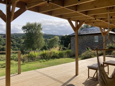 A wooden deck with a table and hammock at Treovis Cottage in Callington