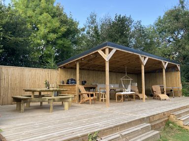 An outdoor seating area with a wooden table and hammock at Treovis Cottage in Callington