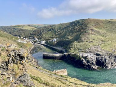 A coastal view with water, cliffs, and buildings at Treovis Cottage in Callington