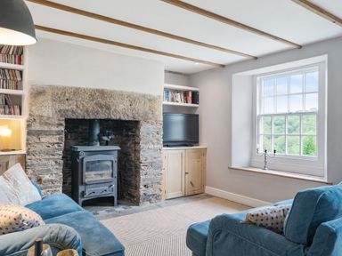 A living room with a fireplace and wood stove at Treovis Cottage in Callington