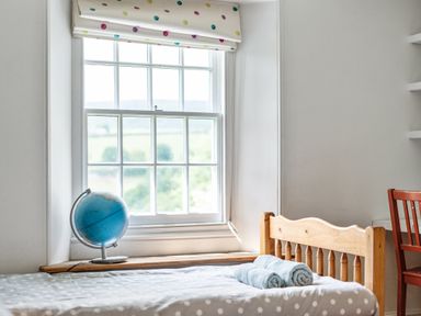A bedroom with a window, globe, and bed at Treovis Cottage in Callington
