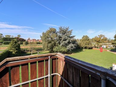 A balcony view overlooking trees and grass at East Cottage in East Knapton near Rillington
