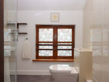 A bathroom with a toilet and a window at The Milking Shippon at Thorne, Langtree near Great Torrington