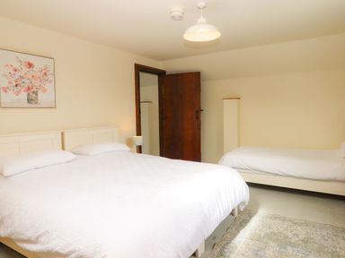 A bedroom with two beds and a picture on the wall at The Milking Shippon at Thorne Langtree near Great Torrington