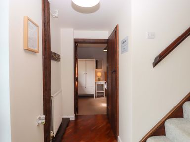 A hallway with stairs and a door leading to another room at The Milking Shippon at Thorne, Langtree near Great Torrington