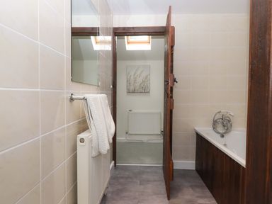 A bathroom with a bathtub and a towel rack at The Milking Shippon at Thorne Langtree near Great Torrington