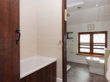 A bathroom with a bathtub and toilet at The Milking Shippon at Thorne near Great Torrington