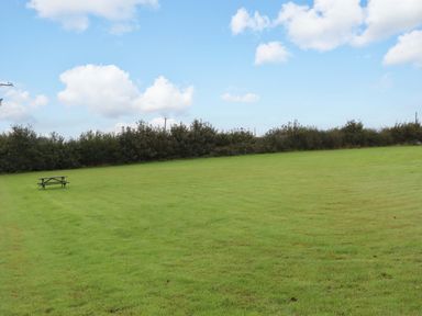 An open grassy area with a picnic table and hedge at The Milking Shippon at Thorne Langtree near Great Torrington