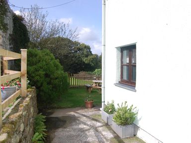 A garden with a stone wall and table at The Milking Shippon at Thorne near Great Torrington