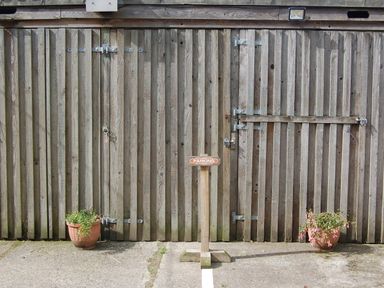 An outdoor area with a wooden door and parking sign at The Milking Shippon at Thorne Langtree near Great Torrington