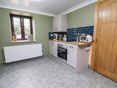 A kitchen with cabinets and appliances at Ty Cerrig apartment
