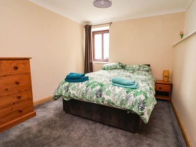 A bedroom with a bed and dresser at Ty Cerrig apartment