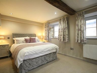 A bedroom with a bed and nightstand at The Coach House in Burford
