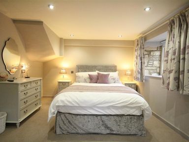 A bedroom with a bed and dresser at The Coach House in Burford