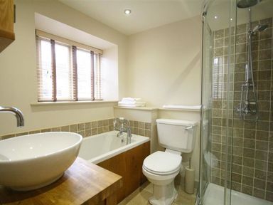 A bathroom with a bathtub, toilet, and shower at The Coach House in Burford