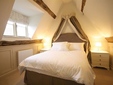 A bedroom with a bed and nightstand at The Coach House in Burford