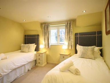 A bedroom with two beds and a window at The Coach House in Burford