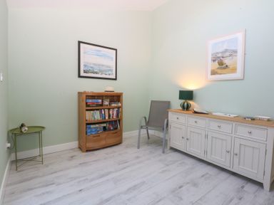 A room with a bookshelf and a chair at 2 Lon Y Dryw in Trearddur Bay