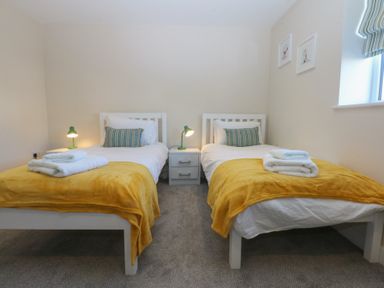 A bedroom with two beds and nightstands at 2 Lon Y Dryw in Trearddur Bay