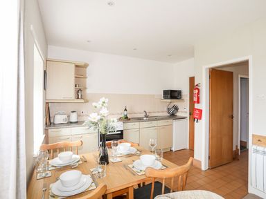 A kitchen with dining table and appliances at Ceiriad - 9 Ty'n Don in Llanengan near Abersoch