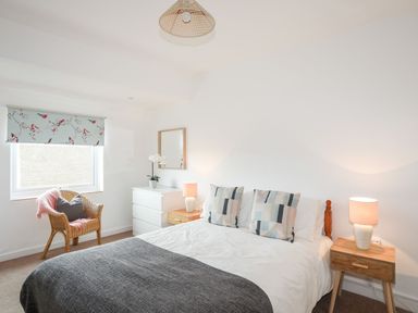 A bedroom with a bed, lamps, and a chair at Ceiriad - 9 Ty'n Don in Llanengan near Abersoch