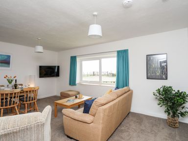 A living room with a table and television at Oer - 8 Ty'n Don Llanengan near Abersoch