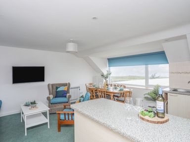 A living room with a dining table and television at Ysgo - 6 Ty'n Don in Abersoch