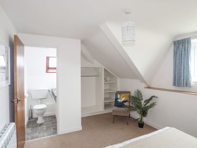 A bedroom with a chair and a view of a bathroom at Ysgo - 6 Ty'n Don Abersoch