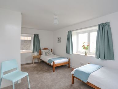 A bedroom with two beds and a table at Ysgo - 6 Ty'n Don in Abersoch