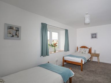 A bedroom with two beds and a window at Ysgo - 6 Ty'n Don Abersoch