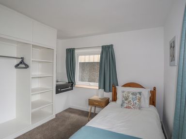 A bedroom with a bed and shelving unit at Ysgo - 6 Ty'n Don Abersoch