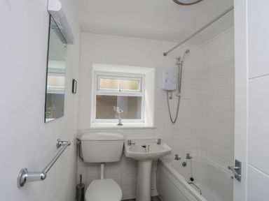 A bathroom with a mirror, toilet, sink, and bathtub at Ysgo - 6 Ty'n Don Abersoch