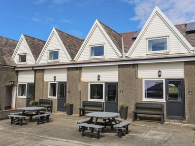 A building with multiple doors and tables outside at Ysgo - 6 Ty'n Don Abersoch
