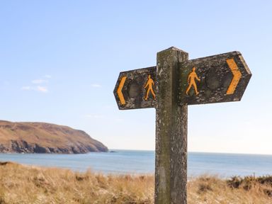 A signpost indicating walking directions near the ocean at Ysgo - 6 Ty'n Don, Abersoch