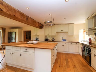 A kitchen with wooden cabinets and appliances at Millbarn in Crowcombe