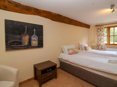 A bedroom with two beds and a painting at Millbarn in Crowcombe