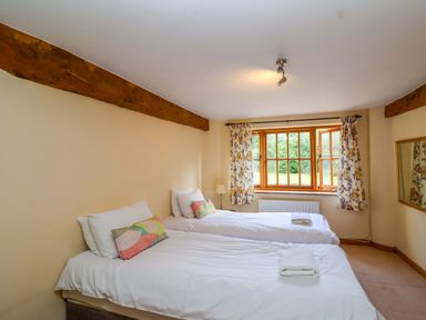 A bedroom with two beds and a window at Millbarn in Crowcombe