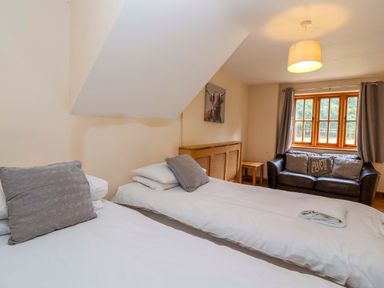 A bedroom with two beds and a sofa at Millbarn in Crowcombe