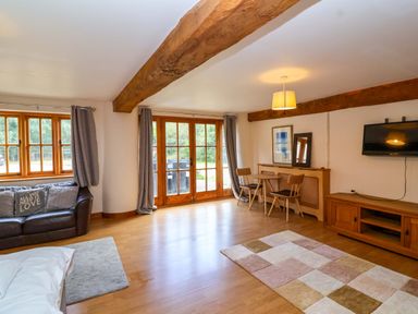 A living room with a sofa and a dining area at Millbarn in Crowcombe