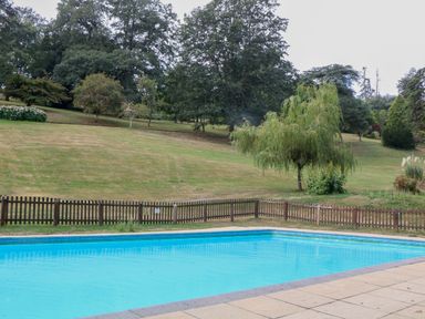 An outdoor swimming pool with a fenced area at Sheplegh Court Garden Apartment Blackawton near Dartmouth