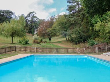 A swimming pool surrounded by grass and trees at Sheplegh Court Garden Apartment in Blackawton near Dartmouth