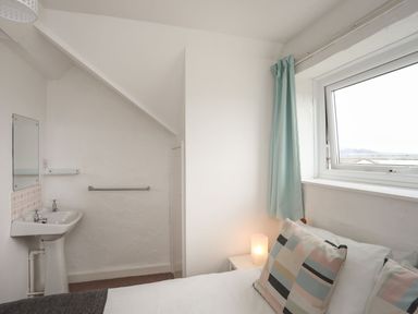 A bedroom with a window and a sink at Penrhyn - 4 Ty'n Don