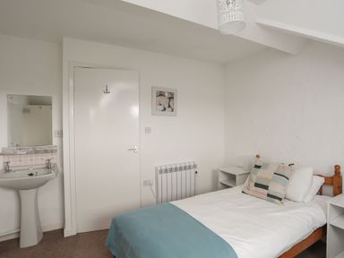 A bedroom with a bed and a sink at Penrhyn - 4 Ty'n Don