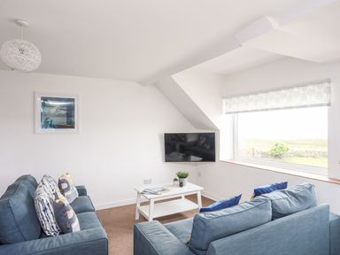 A living room with a TV and a coffee table at Towyn - 7 Ty'n Don
