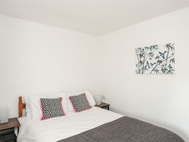 A bedroom with a bed and wall art at Towyn - 7 Ty'n Don