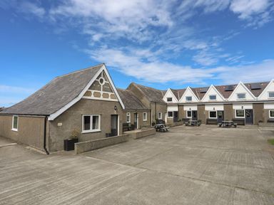 An outdoor area with multiple buildings and benches at Towyn - 7 Ty'n Don