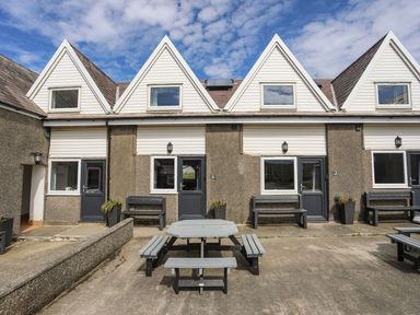 A building with outdoor seating and windows at Towyn - 7 Ty'n Don